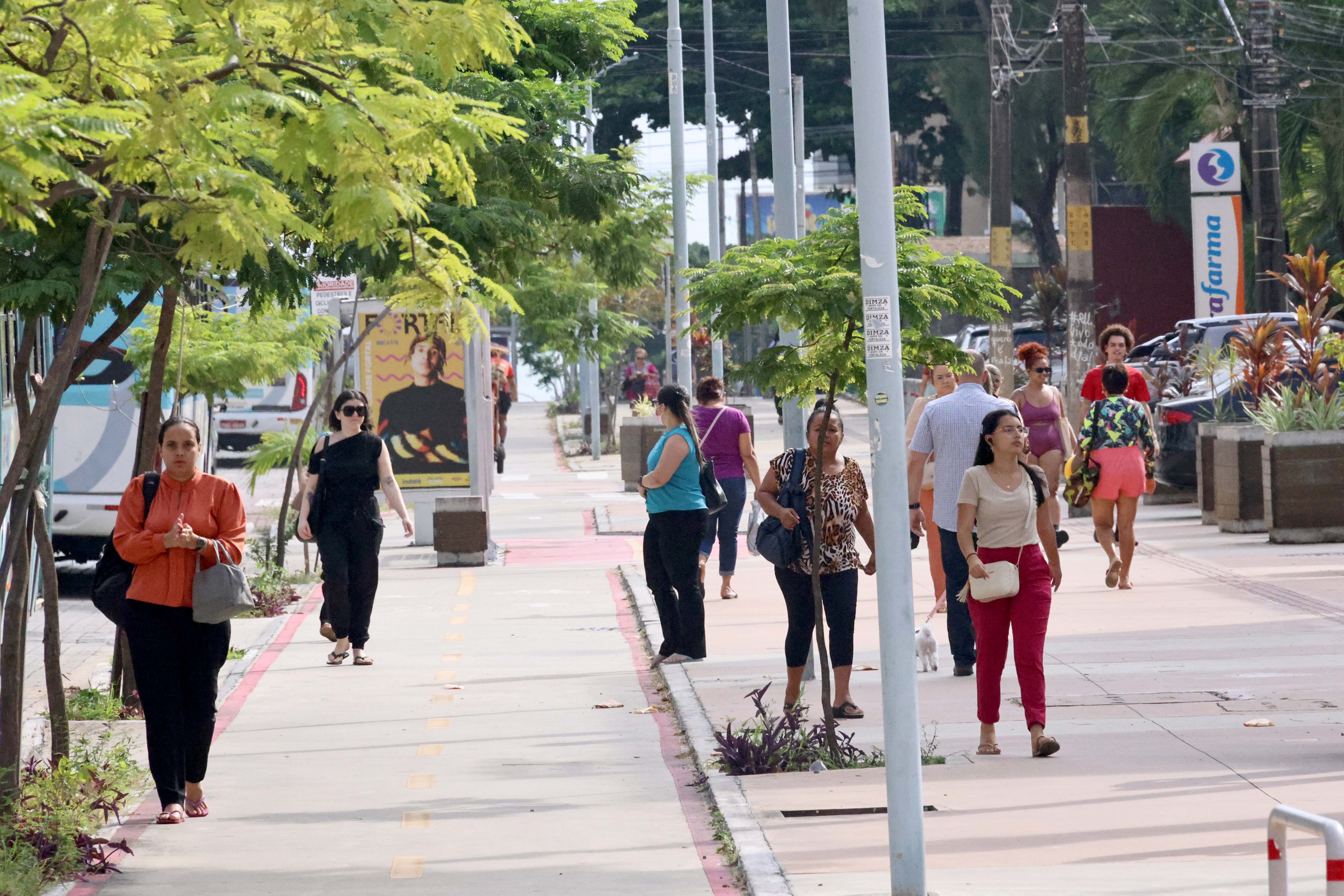 pessoas caminhando em uma rua arborizada de Fortaleza